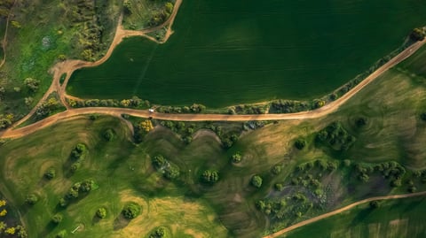 Drone flying over agricultural field on sunny day against dramatic sky