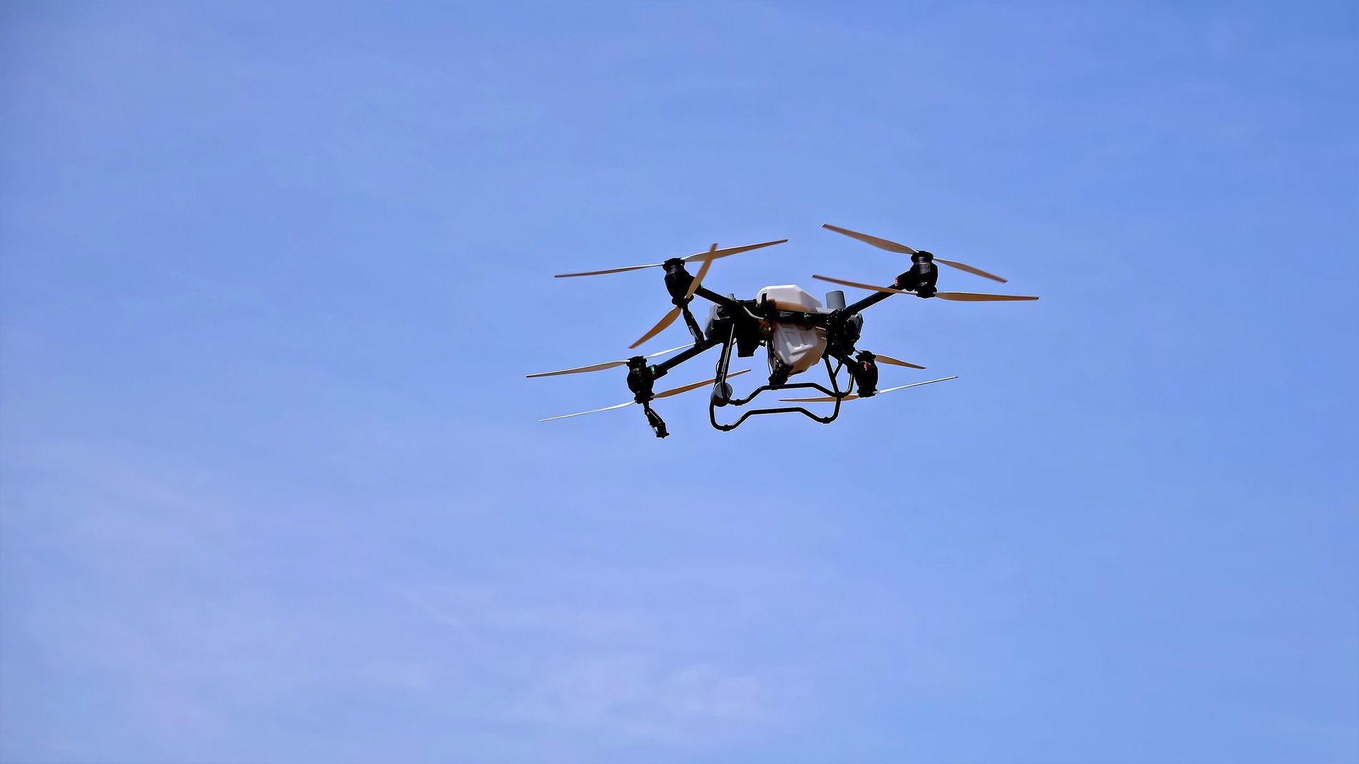 Industrial drone flying in clear blue sky, representing professional aerial capabilities