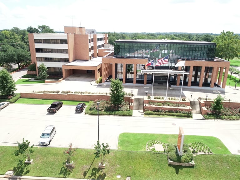 Aerial view of a modern brick institutional building with parking lot and landscaped grounds