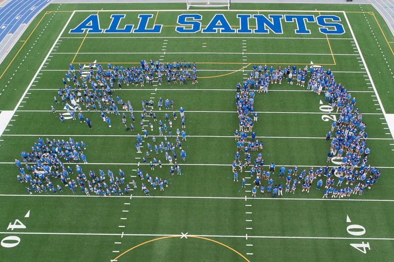 Aerial view of All Saints marching band forming numbers on football field