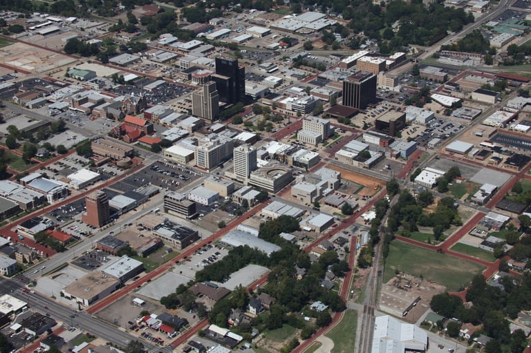 Aerial view of downtown city area with high-rise buildings, trees, and streets in a suburban/urban landscape