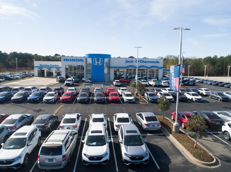 Aerial view of a Honda dealership with a blue building surrounded by rows of parked vehicles in the lot