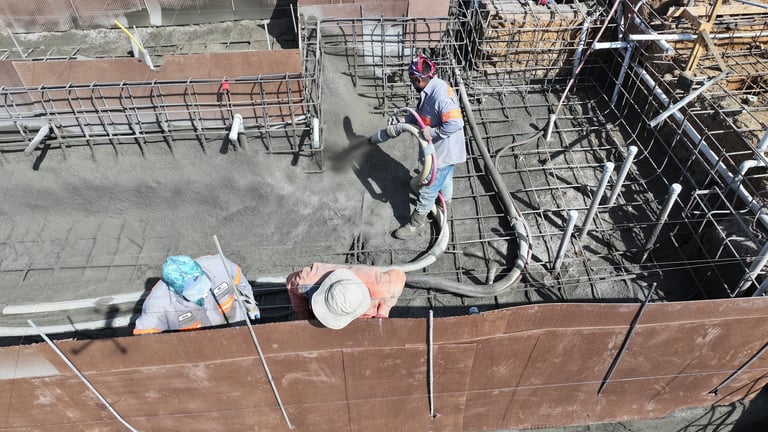 Overhead view of construction site with worker on concrete floor surrounded by metal reinforcement and equipment