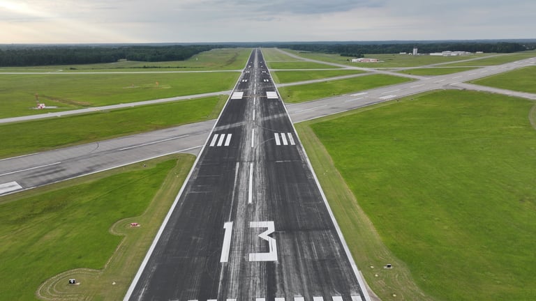 Aerial view of runway 13 with white center line markings and green grass fields on either side