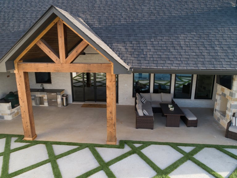 Modern patio area with wooden pergola, lounge chairs, and geometric paved walkway adjoining house