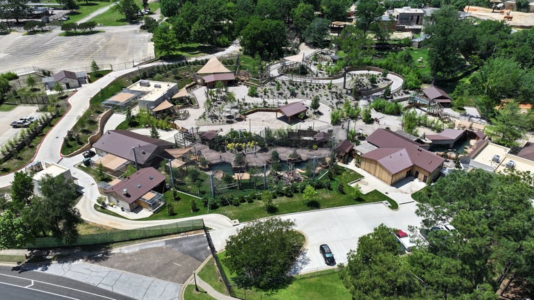 Aerial view of a large luxury residential estate with multiple buildings, curved driveway, manicured grounds, and surrounding trees